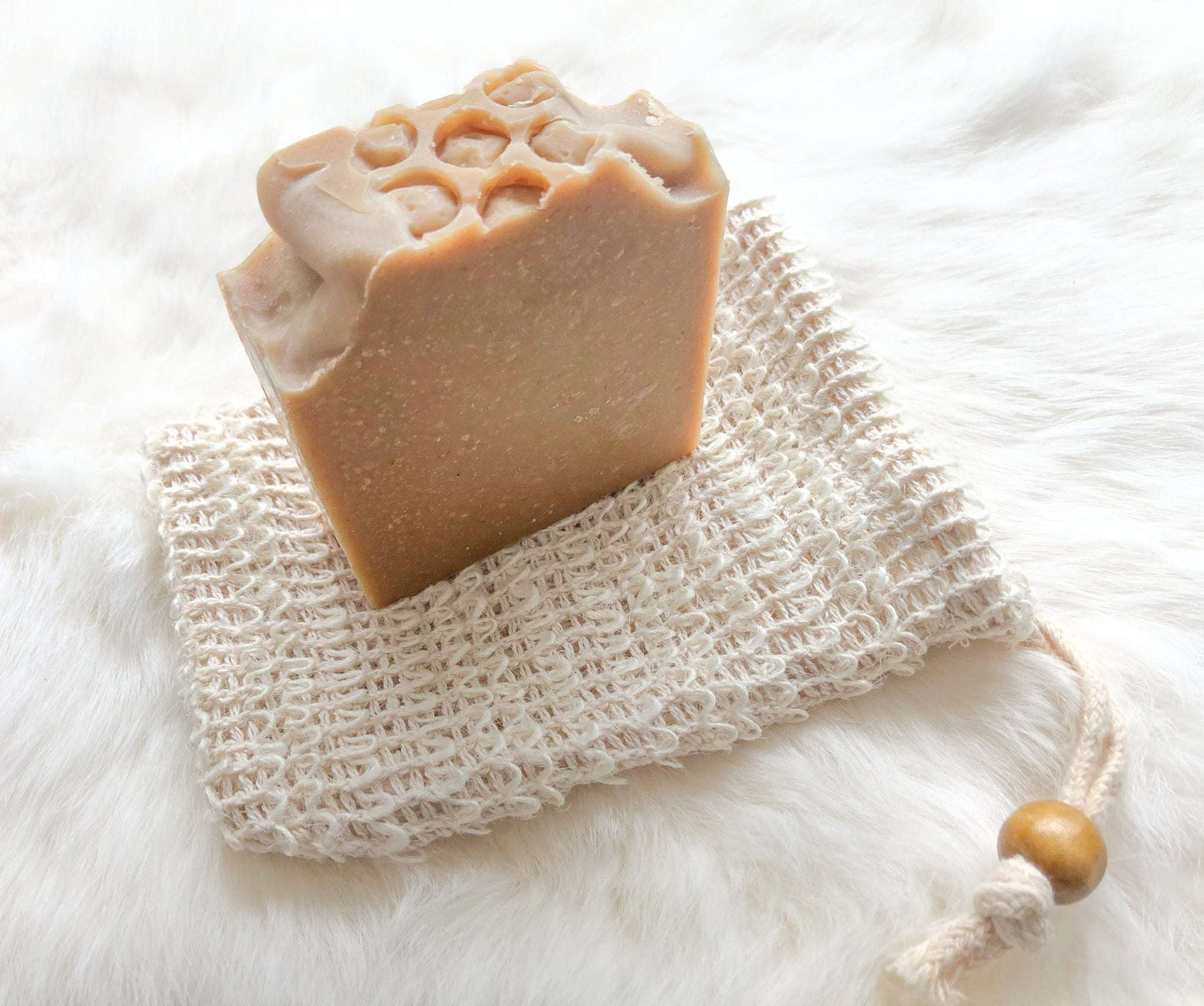 Soap saver bag made of natural sisal, holding a bar of soap, used for exfoliating skin and keeping soap dry in the shower.